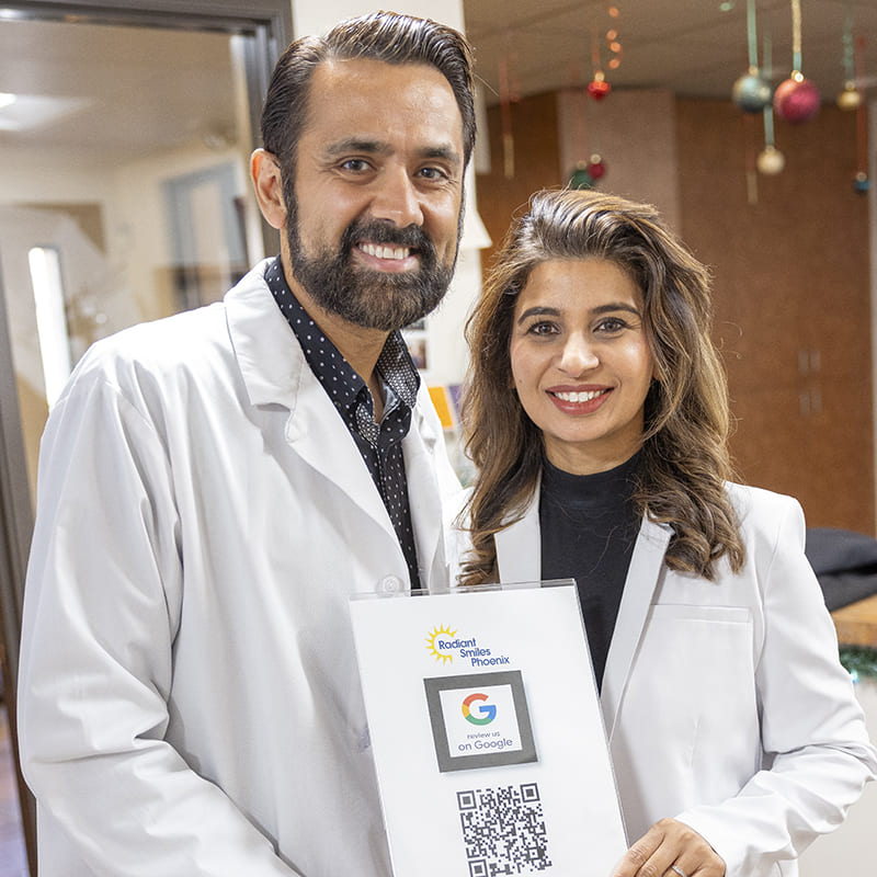 Dr. Sandhu and Dr. Bajwa holding a Google review QR code